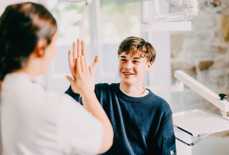 Zahnärztin Dr. Simona Huber und ein junger Patient geben sich ein High Five