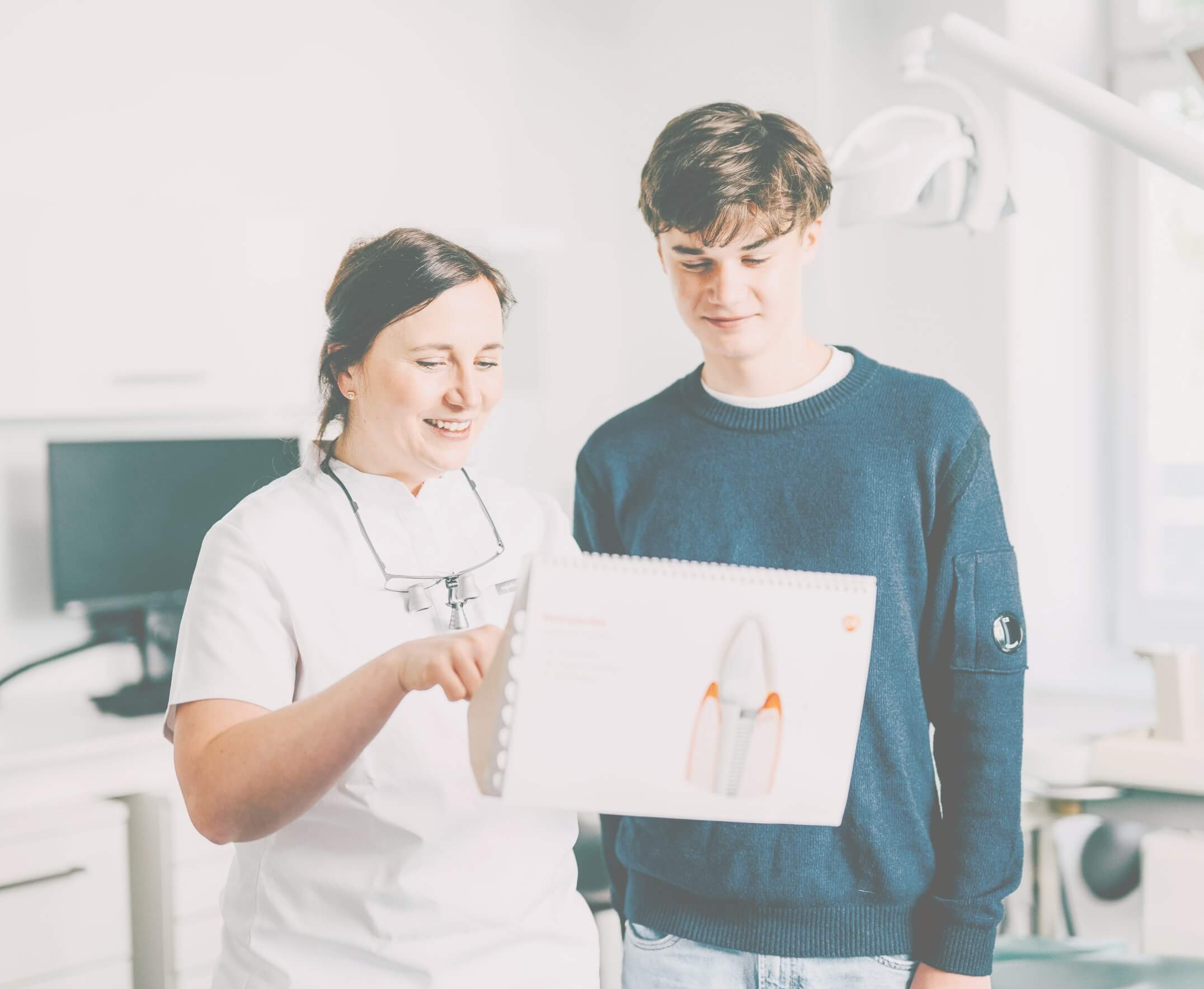 Zahnärztin Dr. Simona Braun erklärt einem jugendlichen Patienten etwas mit Hilfe von Beispielmaterial
